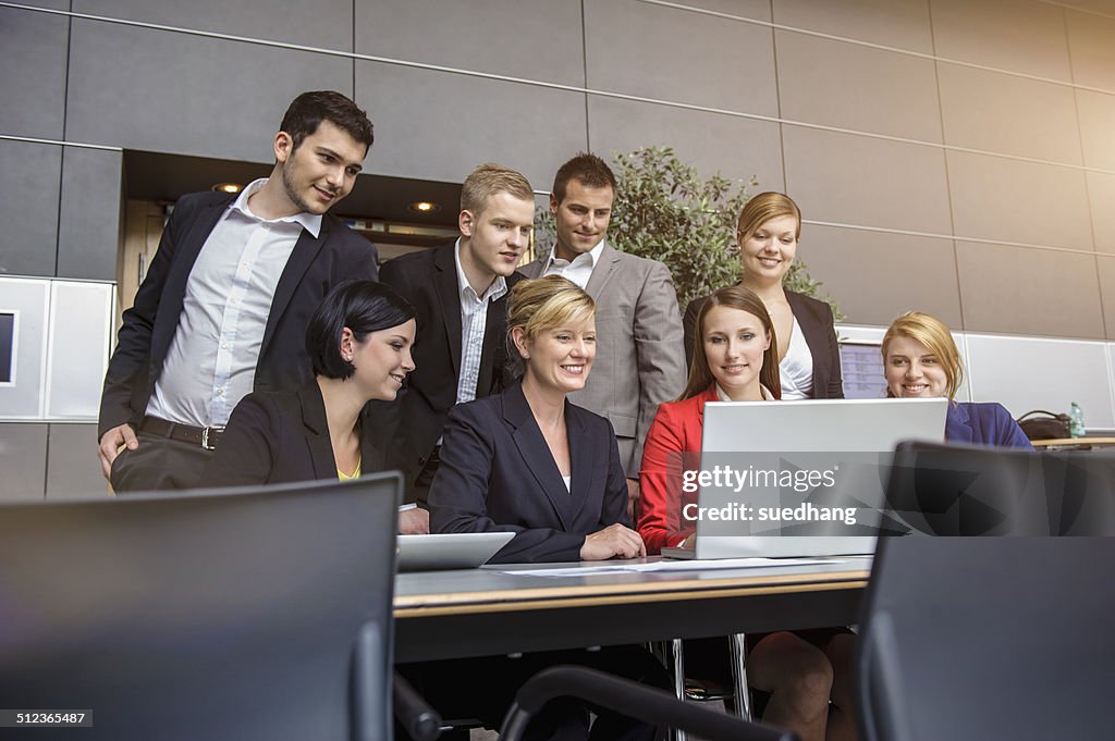 Businesswoman and office team looking at laptop