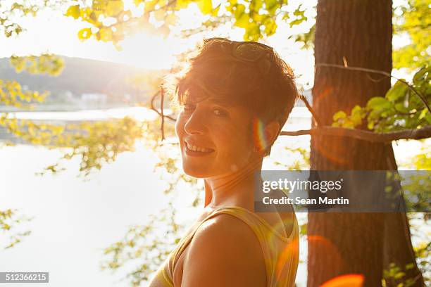 portrait of mid adult woman by lakeside at sunset - porträt frau blick in ferne stock-fotos und bilder