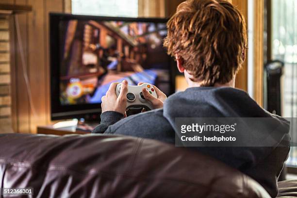 teenager playing video games at home - console stockfoto's en -beelden