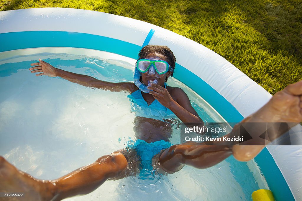 High angle view of girl in snorkel mask in garden paddling pool