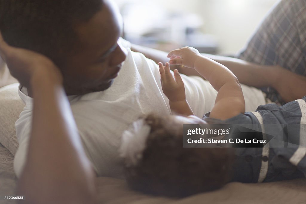 Father lying with baby daughter