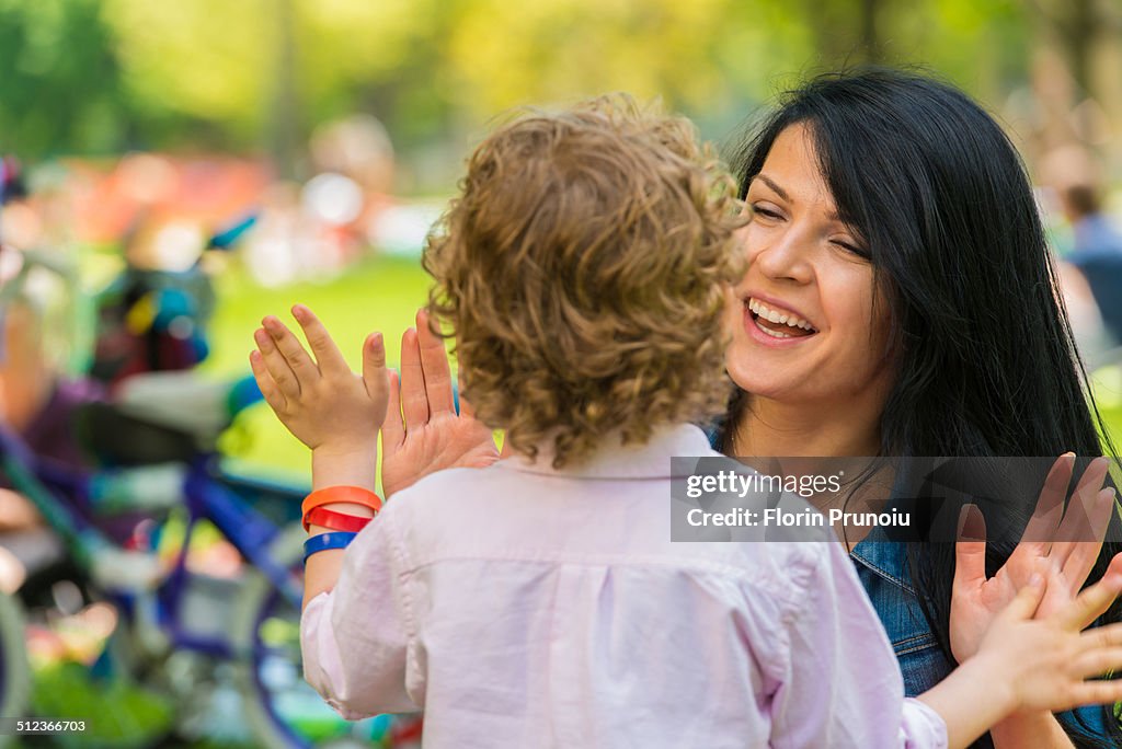 Young mother and son with hands together in park