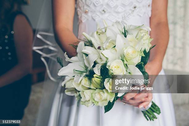 bride holding bouquet of white flowers - matrimoni foto e immagini stock