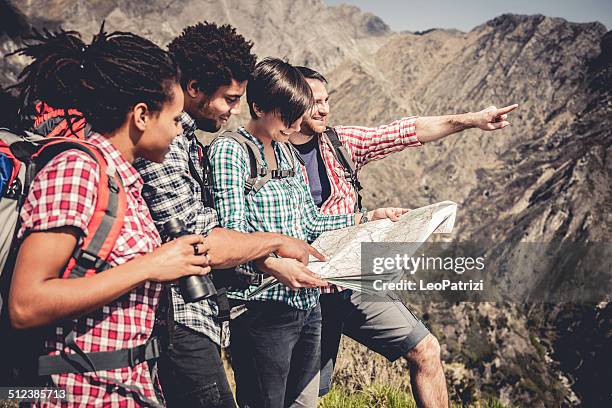 gruppe von freunden in mountaing suche auf der karte - bergsteiger mit karte und rucksack stock-fotos und bilder