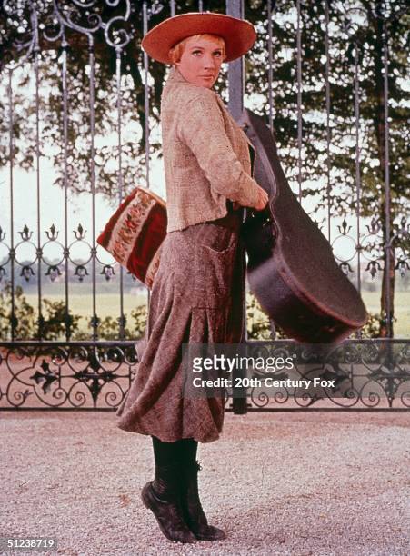 British actor Julie Andrews holds a guitar case and a carpet bag in a still from the film 'The Sound of Music' directed by Robert Wise.
