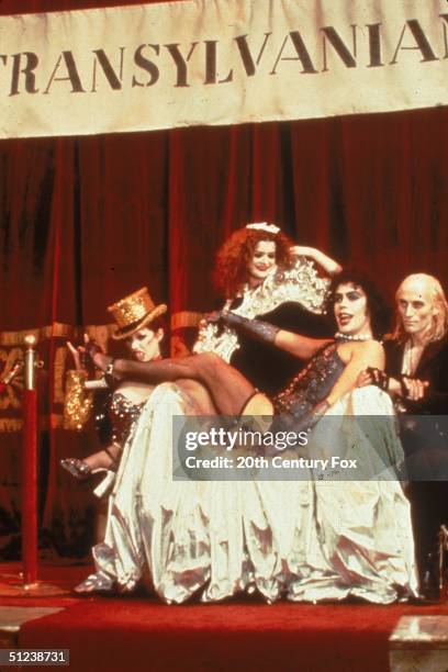 British-born actor Tim Curry, as Doctor Frank-N-Furter, reclines in a chair surrounded by Nell Campbell, Patricia Quinn and Richard O'Brien in a...