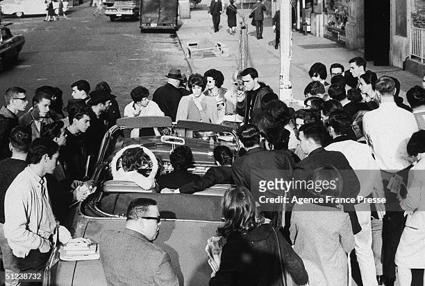 22nd November 1963, A crowd in New York gathers around a convertible car to listen to radio reports of President John F Kennedy's assassination.