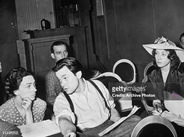American actor, writer, producer and director Orson Welles talking with Agnes Moorehead on a theatre stage with members of the Mercury Theatre.