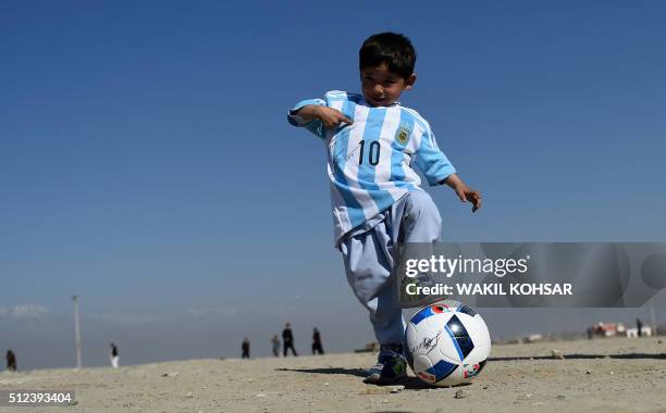 Afghan boy five-year-old Murtaza Ahmadi, a young Lionel Messi fan, plays football as he wears a donated and signed shirt by Messi on a field in Kabul...