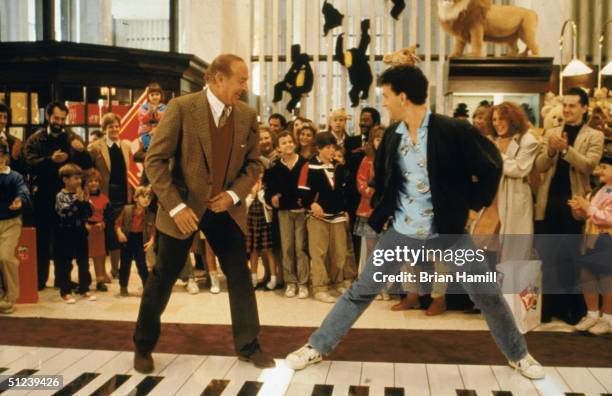 American actors Robert Loggia, left, and Tom Hanks stand on a giant piano keyboard at the FAO Schwartz toy store in a still from the film 'Big'...