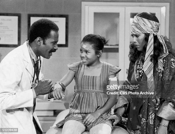 Circa 1978, American actor Bob Delegall examines a scrape on the arm of child actor and singer Janet Jackson as American actor Ja'net DuBois looks on...