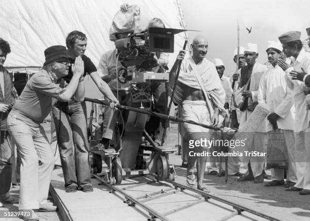 British director Richard Attenborough, left, and his camera crew prepare to shoot a scene with actor Ben Kingsley as Mahatma Gandhi, and group of...