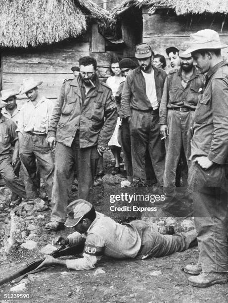 Circa 1955, Cuban revolutionary Fidel Castro observes as a member of his guerilla army tests his shotgun, Sierra Maestro, Cuba, 1950s.