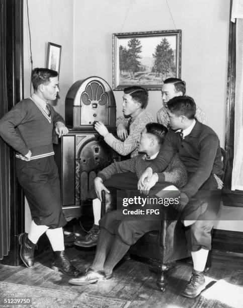 Circa 1930, A group of young Asian men sit down to listen to a radio broadcast.
