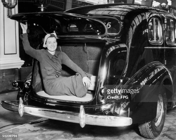 15th October 1935, A young woman demonstrates the size of the boot of a Buick Straight Eight, a ?664 De Luxe model at the Motor Show in Olympia,...