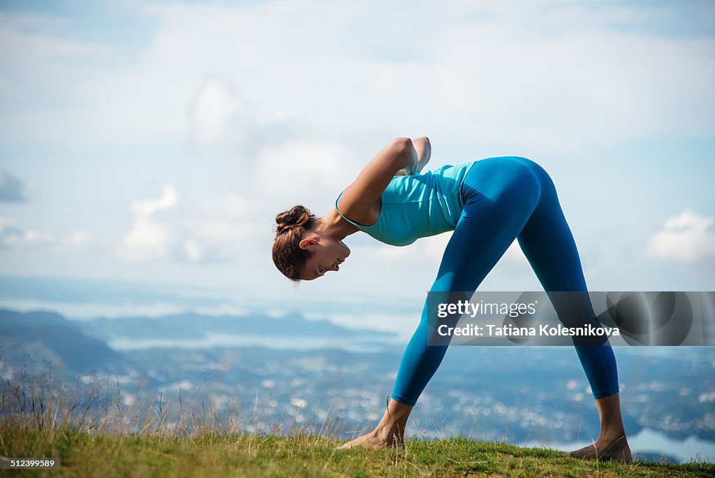 Woman practicing yoga on top of a mountain