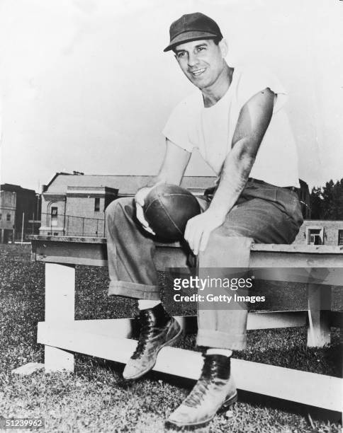 Circa 1955, Portrait of American football coach Paul Brown holding a football while sitting on a table, 1950s. Brown coached the Cleveland Browns,...