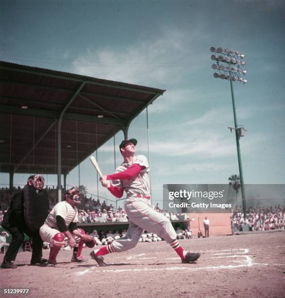 American baseball player Stan Musial watches the ball as he follows through after a hit during a game circa 1955. Musial wears the uniform of the St....