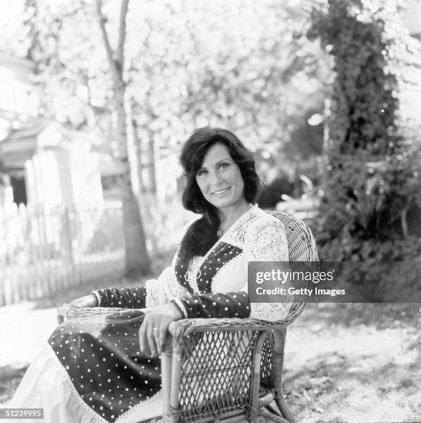 Portrait of American country singer and songwriter Loretta Lynn seated outdoors on a lawn.