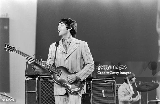 British rock musician Paul McCartney playing on stage during The Beatles', last tour. Drummer Ringo Starr is visible in the background.