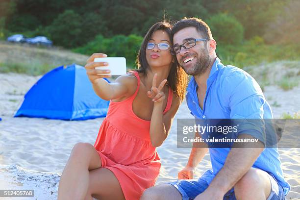 happy couple making faces on the beach - young couple red sunny stock pictures, royalty-free photos & images