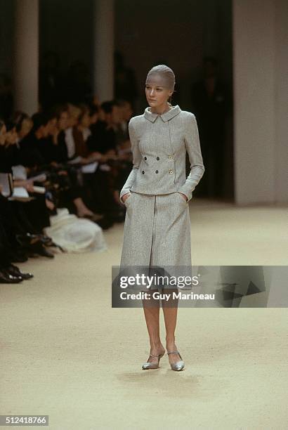 Model on the runway at the Spring/Summer 1999 Chanel couture collection designed by Karl Lagerfeld, wearing a gray tweed skirt suit comprised of box...
