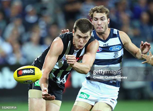 Mason Cox of the Magpies handballs whilst being tackled by Jackson Thurlow of the Cats during the 2016 NAB Challenge match between the Geelong Cats...