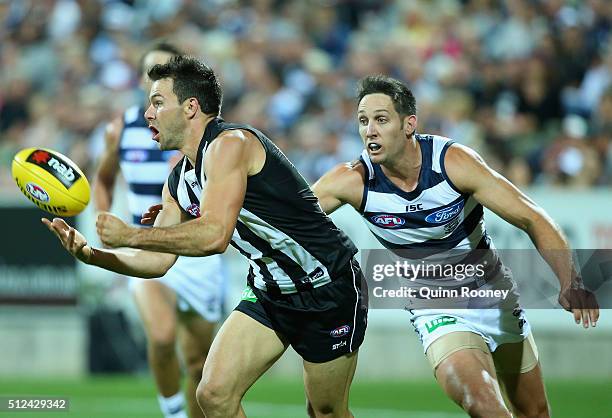Levi Greenwood of the Magpies handballs whilst being tackled by Harry Taylor of the Cats during the 2016 NAB Challenge match between the Geelong Cats...