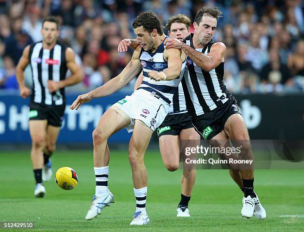 Sam Menegola of the Cats kicks whilst being tackled by Steele Sidebottom of the Magpies during the 2016 NAB Challenge match between the Geelong Cats...