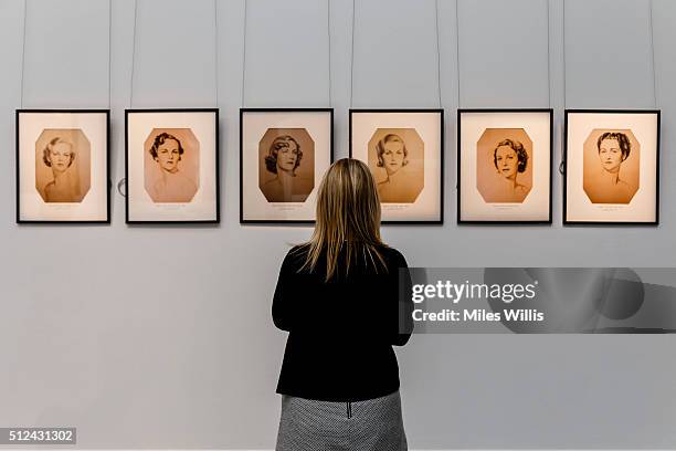 Member of Sotheby's staff poses with six portraits of the Mitford sisters, after William Acton during a behind the scenes look at the personal...