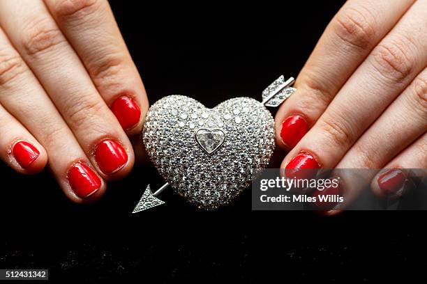 Member of Sotheby's staff holds a diamond brooch given to the Duchess by her husband Andrew Cavendish, 11th Duke of Devonshire to mark their diamond...