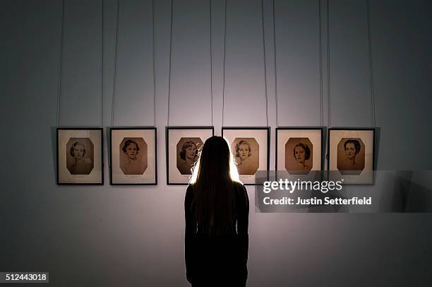 Sotheby's employee stands infront of a series of portraits of the Mitford Sisters during the pre-auction preview of the personal collection of...