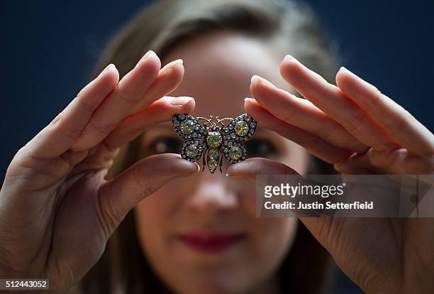 Sotheby's employee holds a diamond and ruby butterfly Brooch, circa 1880 with an estimated auction value of £25,000-35 during the pre-auction preview...