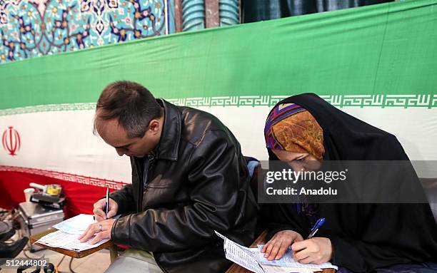 Iranian voters register before casting their vote for both parliamentary elections and the Assembly of Experts at a polling station in Tehran on...