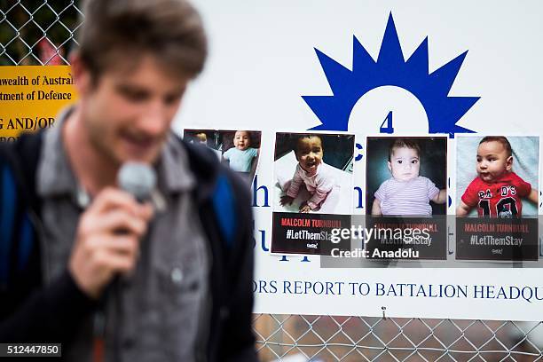 Posters of young babies hung on the gate of a refugee detention centre as a speaker addresses the crowd during a candlelight vigil as protestors...