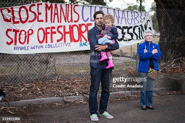 Father holds onto his young daughter as he stands in front of a large banner demanding the closure of manus island detention centre during a...