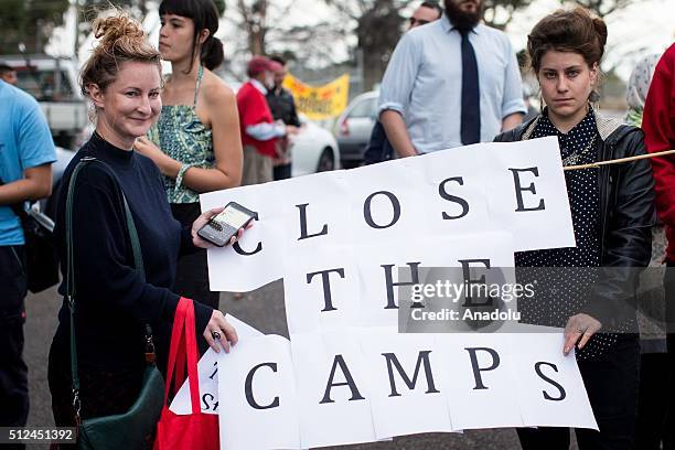 Two protestors hold a banner reading 'Close the camps' outside a refugee detention centre during a candlelight vigil as protestors stand in...