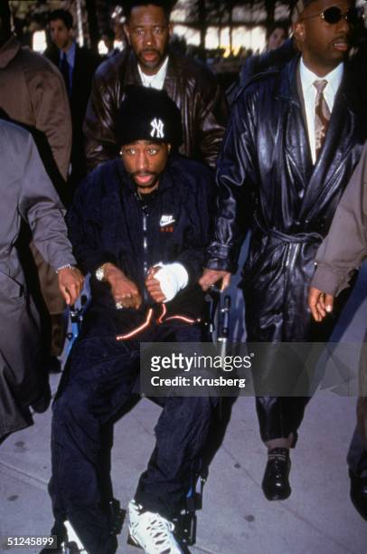 1st December 1994, American rapper and actor Tupac Shakur is helped out of court in a wheechair the day after his shooting.