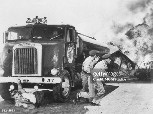 British actor Cary Grant attempts to crawl out from under an exploding oil truck, while the drivers flee in a still from director Alfred Hitchcock's...
