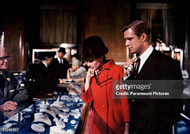 Belgian-born actor Audrey Hepburn and American actor George Peppard browse through jewelry at Tiffany's department store in a scene from director...