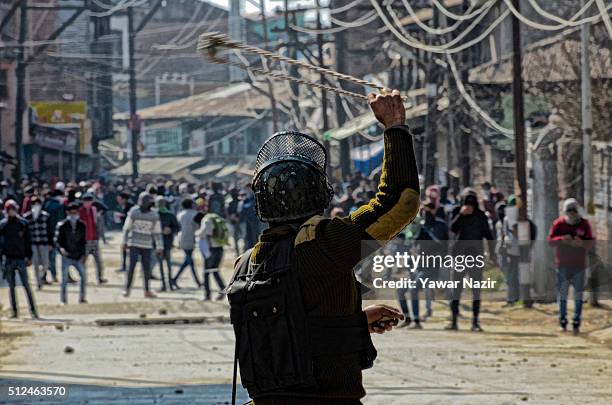 Indian paramilitary soldier throws a stone at Kashmiri Muslim protesters with his sling shot during an anti India protest on February 26, 2016 in...
