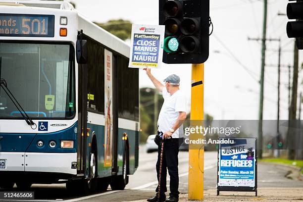 Protestor holds a placard reading close Manus island as a bus drives past during a candlelight vigil as protestors stand in solidarity with refugees...