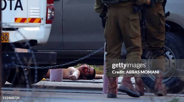 Israeli security forces gather around the body of a Palestinian man who tried to stab Israeli soldiers before being shot dead at a checkpoint near...