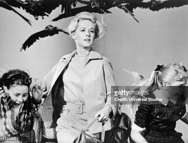 American actor Tippi Hedren and a group of children run away from the attacking crows in a still from the film 'The Birds' directed by Alfred...
