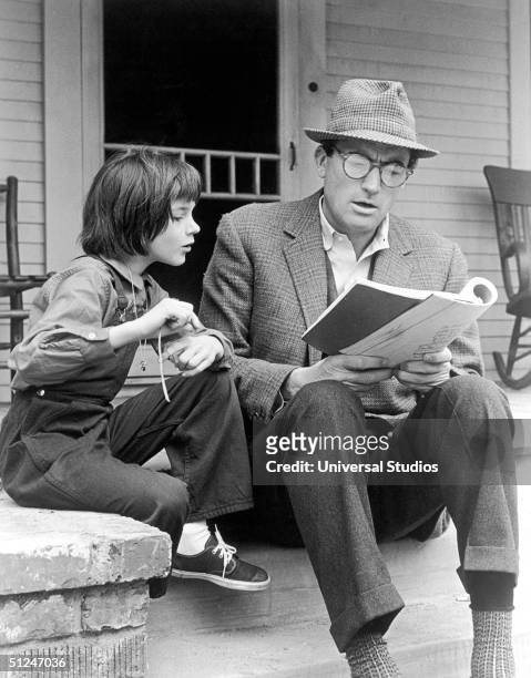 American actors Gregory Peck and Mary Badham review the script for the film, 'To Kill a Mockingbird' directed by Robert Mulligan, on the set of the...