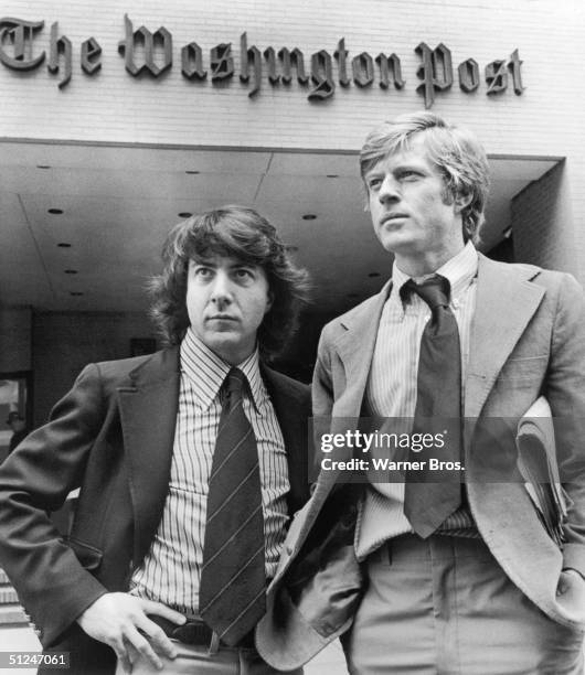 Promotional portrait of Robert Redford, right, and Dustin Hoffman standing in front of the Washington Post Building in a still from director Alan J...