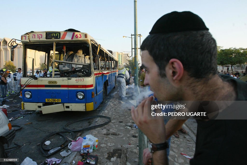 An Israeli man looks at a destroyed bus