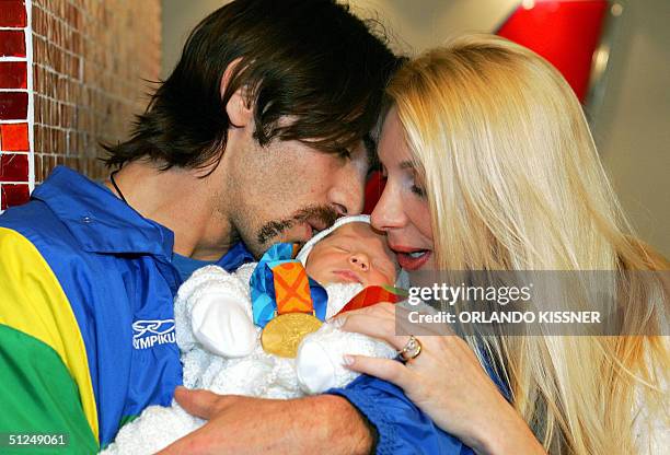 Brazilian volleyball player Gilberto Giba Godoy, Gold medal in Athens, kisses his daughter Nicoll next to his wife Cristiane Pirv, after arriving to...