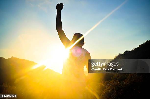 reaching the glory - man rising his fist - winning stock-fotos und bilder