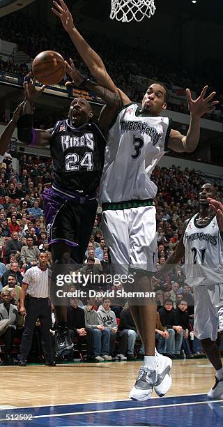 Bobby Jackson of the Sacramento Kings gets fouled on his way to the basket by Loren Woods of the Minnesota Timberwolves at Target Center in...